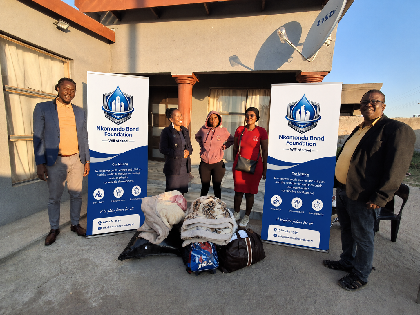 Foundation leaders standing with donation items and branded banners